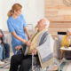 Elderly man in wheelchair accompanied by a nurse