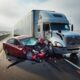 Red passenger car in an angle accident with a semi-truck on the highway.