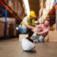 Injured warehouse worker holding his own knee.