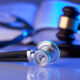 A stethoscope lying on a table next to a gavel.